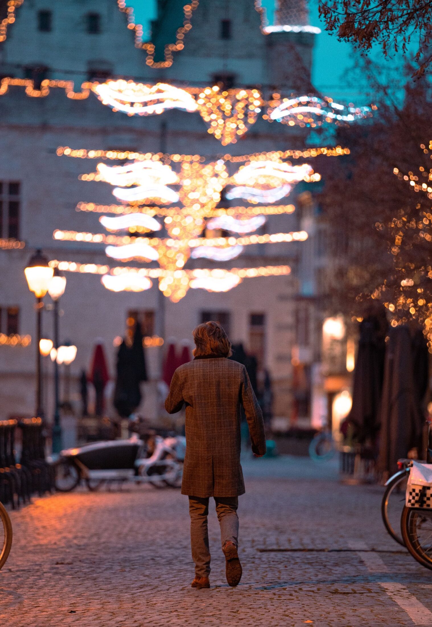 Foto van een man die wandelt door Mechelen met kerstverlichting